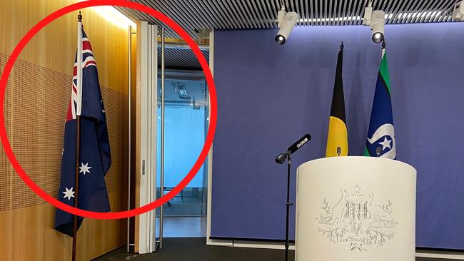 The Australian flag is moved to the side of the room prior to Greens leader Adam Bandt conducting a press conference.