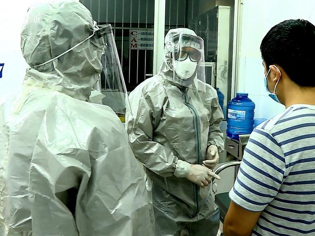 Medical personnel wearing protective suits while interacting with two patients at a hospital in Ho Chi Minh City. Picture: STR/AFP