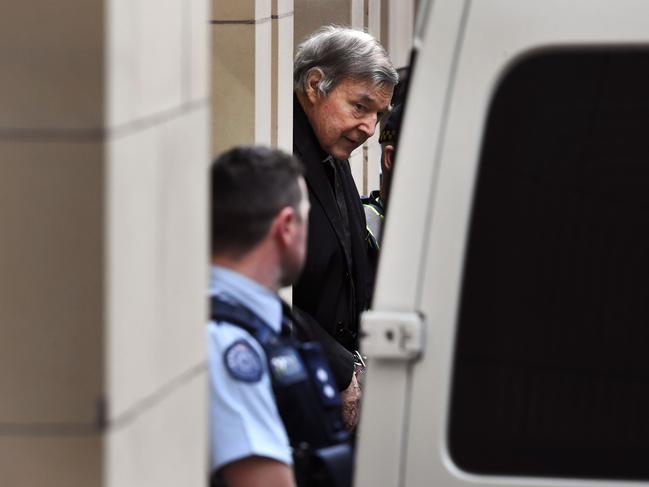 (FILES) This file photo taken on August 21, 2019 shows Australian Cardinal George Pell (C) being escorted in handcuffs from the Supreme Court of Victoria in Melbourne. - Cardinal George Pell will walk free from jail after winning a long-running battle to overturn his child sex abuse convictions in Australia's High Court on April 7, 2020. (Photo by William WEST / AFP)