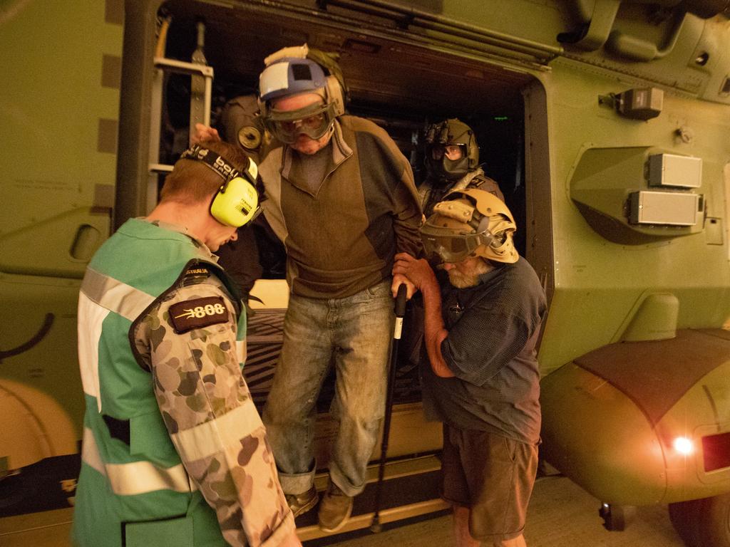 Mr Frank Delaney and Mr Warren Usher of Yalwal, NSW is assisted from an 808 Squadron MRH90 Military Support Helicopter after being evacuated from his remote rural property to the east of the Moreton National Park and in the direct fire front of the Tianjara Fire burning north through ten thousand hectares of national park and bushland. Picture: ADF