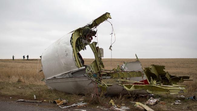 Journalists walk behind parts of the Malaysia Airlines plane Flight MH17 as Dutch investigators (unseen) arrive near the crash site. Picture: AFP