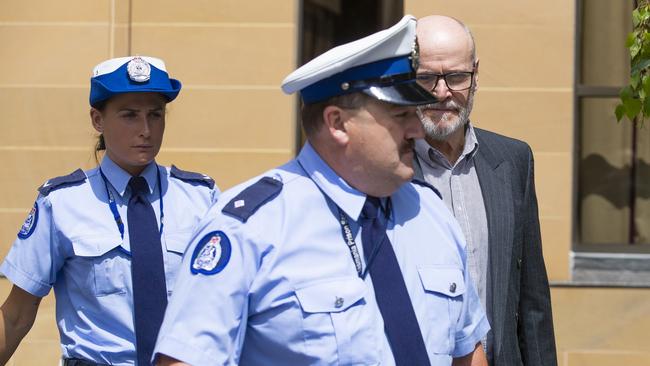 A police officer leads convicted child sex offender Darrel George Harington out of the Supreme Court of Tasmania on Friday.