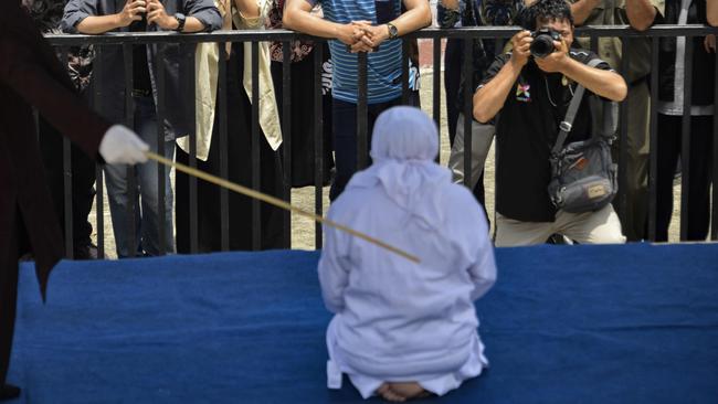 People watch as a woman (C, in white) is whipped in public by a member of the Sharia police in Banda Aceh on September 19, 2019. Picture: AFP