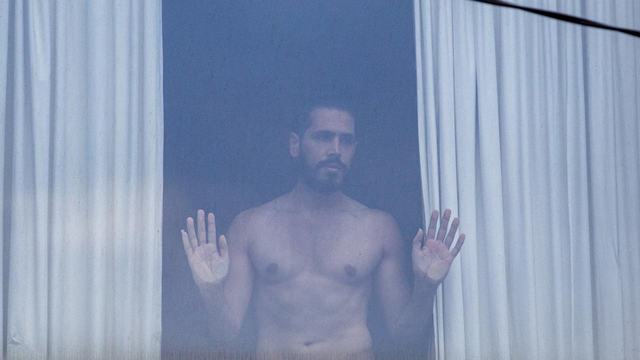 A refugee looks on from behind a window of Park Hotel. Picture: Diego Fedele/Getty Images