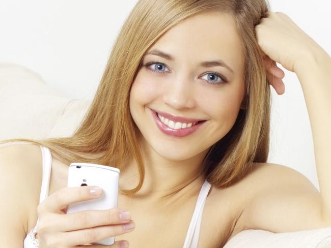 Generic image of happy woman using mobile phone smartphone device on couch.