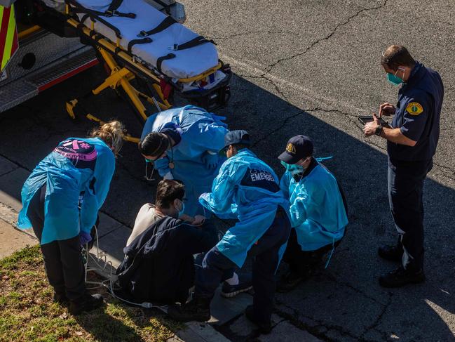 County of Los Angeles paramedics administer oxygen to a potential COVID-19 patient on the footpath before taking him to a hospital. Picture: AFP