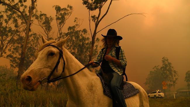 Rhonda Anderson evacuates herself and her horse to safety near Mount Larcom. Picture: AAP/Dan Peled