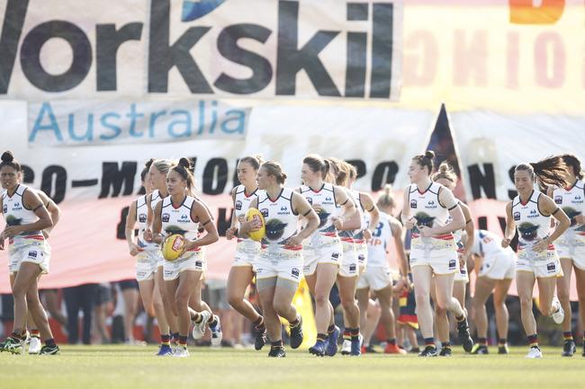 Crows players run out onto Casey Fields in Melbourne for the round 7 AFLW match.