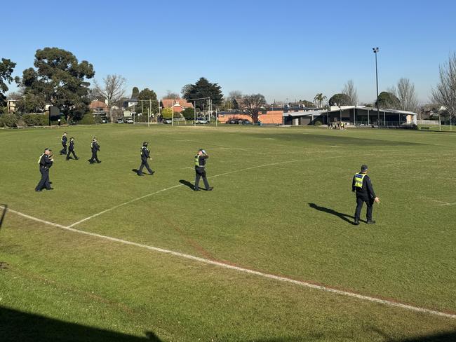 Officers conduct a line search of two footy ovals after the fatal crash.