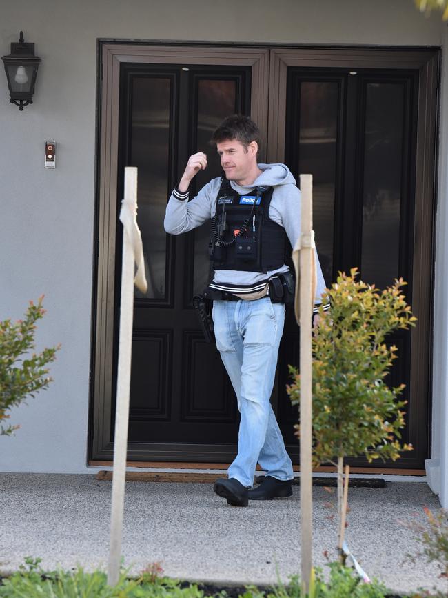 An officer raiding Derek Christopher’s home. Picture jay Town