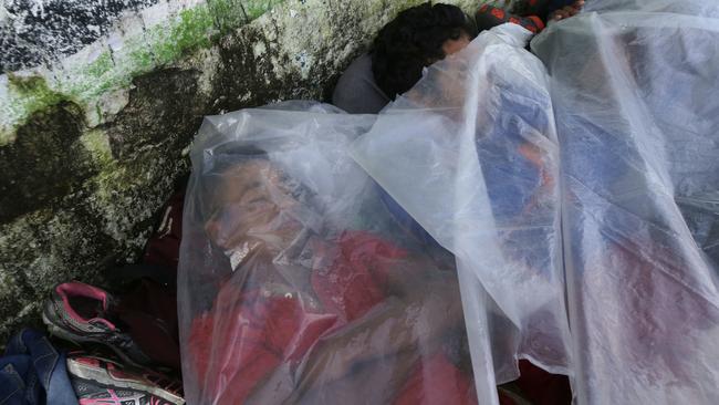 Central American migrants use a piece of plastic as covering as they sleep on a sidewalk in Huixtla, Mexico. Picture: AP.