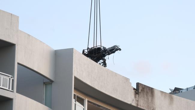 A large crane lifts the wreckage of a Robinson R44 helicopter off the roof top of the Double Tree Hilton hotel into a skip bin, before lowering it to the Cairns Esplanade. The chopper was stolen from Nautilus Aviation and crashed onto the roof at about 1:50am on Monday. Picture: Brendan Radke