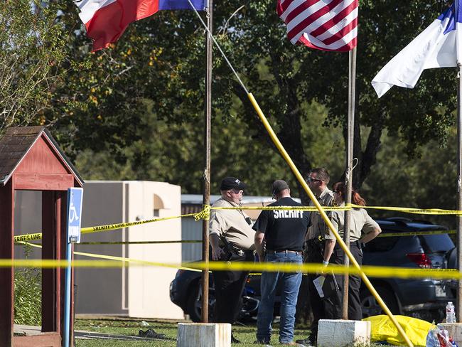 Law enforcement officials stand next to a covered body at the scene of the shooting. Picture: AP