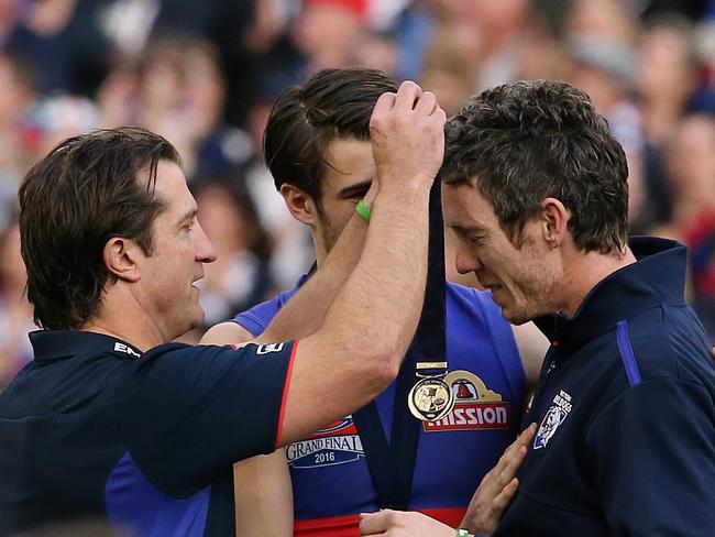2016 AFL Grand Final match between the Western Bulldogs and the Sydney Swans at the Melbourne Cricket Ground (MCG), Melbourne, Australia on October 1, 2016. Luke Beveridge puts his premiership medal over Bob Murphy's neck on the podium with Easton Wood Picture :Wayne Ludbey