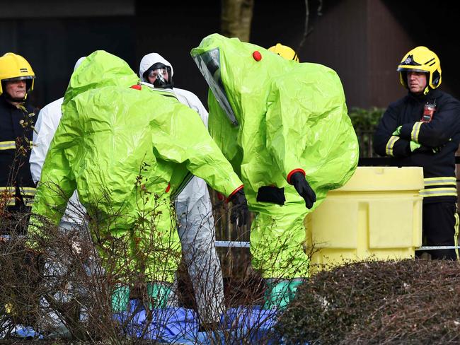 Members of the fire brigade are helped out of their green biohazard suits by colleagues in white protective coveralls after an operation to reattach the tent over the bench in Salisbury. Picture: Ben Stansall/AFP
