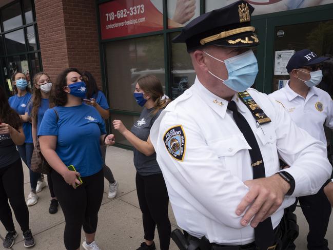 Tanning salon workers, left, stand behind police outside a New York business. Picture: AP