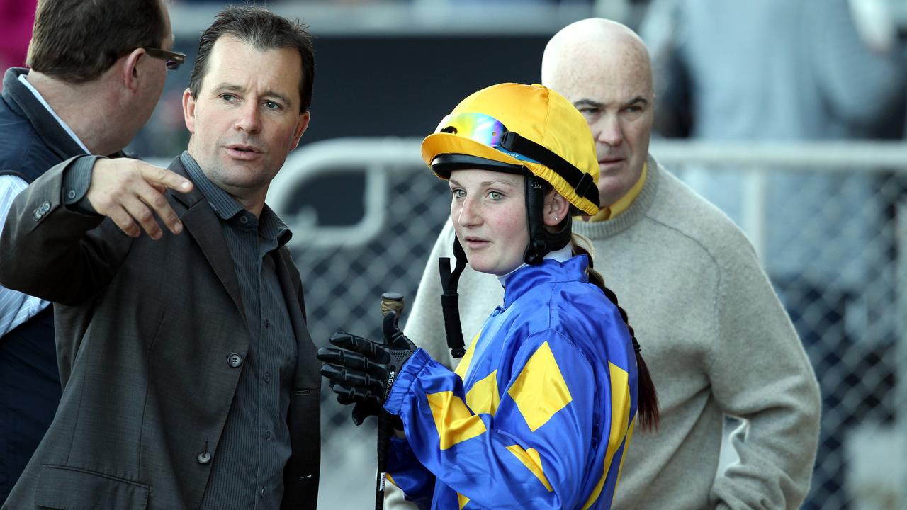 Apprentice jockey Jamie Kah talking to racehorse trainer John MacMillan.