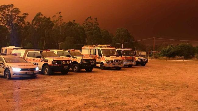 Emergency service vehicles at the school oval in Cann River, with the burning fire in the distance.