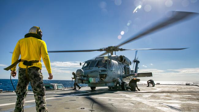 A RAN technician marshals HMAS Arunta’s flight deck crew during MH-60R Seahawk helicopter flying operations. Picture: Department of Defence