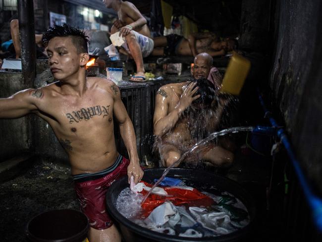 An inmate cooks his dinner as other detainees take a bath inside the Quezon City jail. Picture: Ayee Macaraig