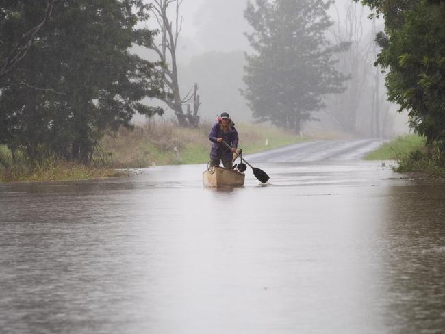 LISMORE, AUSTRALIA. NewsWire Photos. APRIL 5 2024. Rain has caused Eltham Rd in Eltham to close due to flooding on Friday April 5, 2024. Gwilym Summers paddles his canoe to get to the other side of the road.  Photo: NCA NewsWire/ Elise Derwin