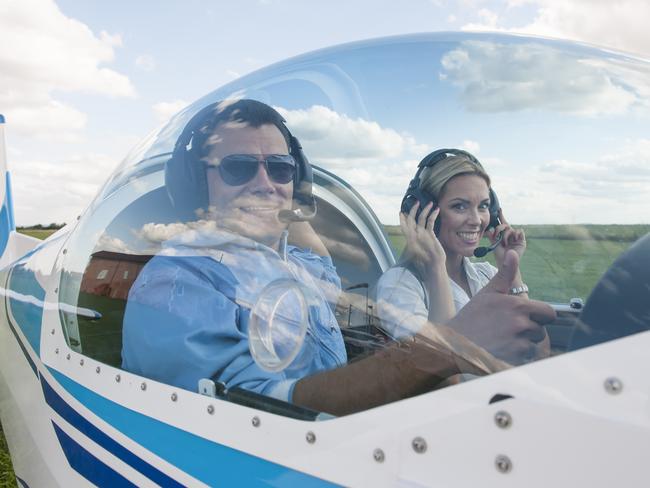 Woman and man pilot looking at camera, showing thumb up, preparing for flying. Istock