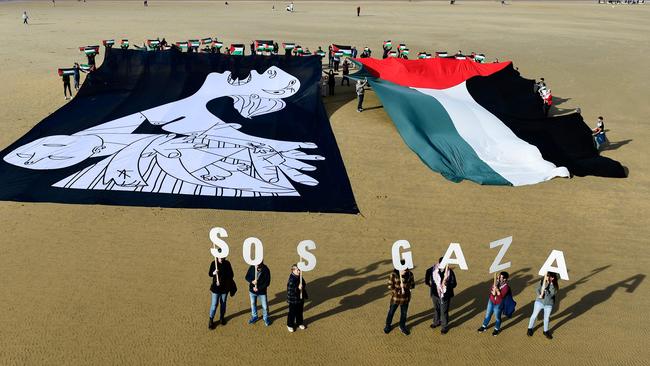 Demonstrators hold a canvas with a detail of Spanish painter Pablo Picasso's masterpiece "Guernica" depicting a mother, and wave a giant Palestinian flag during a protest in solidarity with the Palestinian people. Picture: AFP