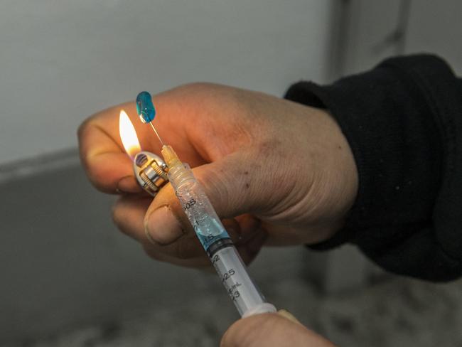 A drug user prepares heroin in a stairwell within the carpark. Picture: Ian Currie