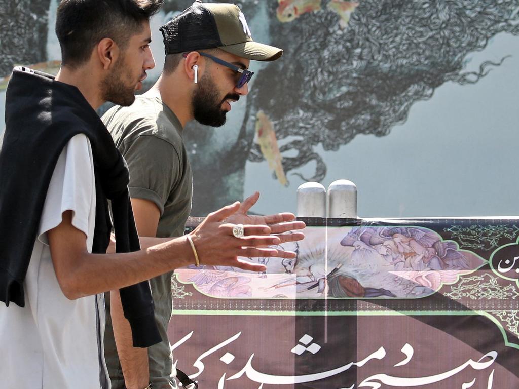 Iranian men chat as they walk past street art in the capital Tehran. Foreign Minister Mohammad Javad Zarif has accused Iran's foes of agitating for war. Picture: AFP