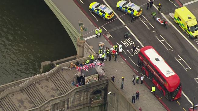 Emergency personnel gather around a body on the southside of Westminster Bridge, where pedestrians were mowed down at random. Picture: ITN via AP