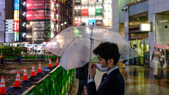 A man wearing a face mask holds an umbrella outside Shinjuku railway station of Tokyo on June 6, 2020. Picture: AFP