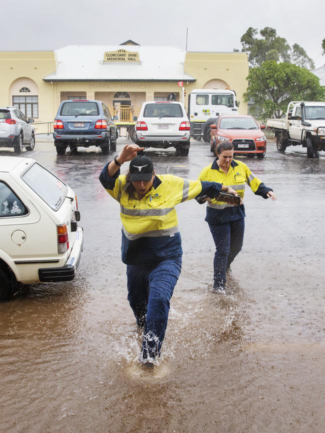 Cloncurry locals walk through flash flooding to stock up on supplies as roads east and west from town are cut off after the region received a deluge of rain up to 300mm in some locations overnight. Photo Lachie Millard