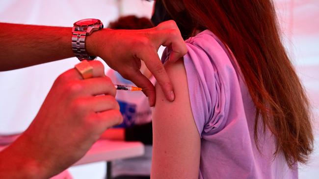 A youth receives a dose of Comirnaty vaccine by Pfizer-BioNTech against Covid-19 on June 29, 2021 at an outdoor vaccination centre set up by the French Red Cross at Republique square in Paris. - Functionning without appointments, the centre gives the priority to delivery drivers. (Photo by MARTIN BUREAU / AFP)