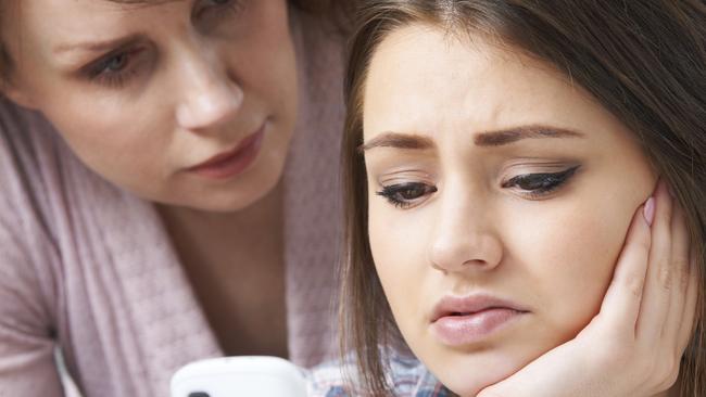 Mother Comforting Daughter Being Bullied By Text Message - Stock Image