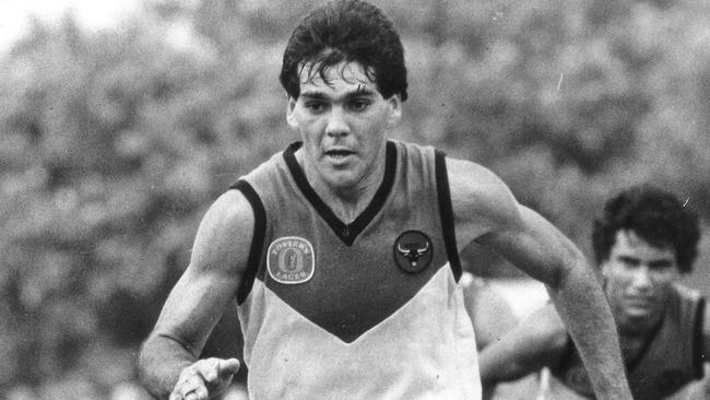 St Mary’s and Territory star Michael Athanasiou wearing the traditional ochre, white and black NTFL jumper against North Melbourne at Gardens Oval in 1988. .