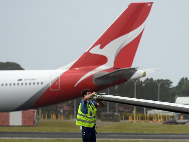 SYDNEY, AUSTRALIA - NewsWire Photos DECEMBER 2, 2020. A man works on a plane as Qantas planes sit idle at Sydney Domestic airport.Picture: NCA NewsWire / Jeremy Piper