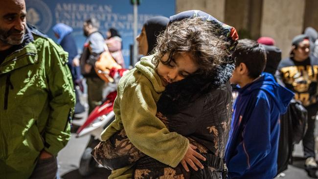 A woman carries her daughter as people displaced by Israeli air strikes shelter at the entrance of American University of Beirut Medical Center in Beirut, Lebanon. Picture: Getty Images