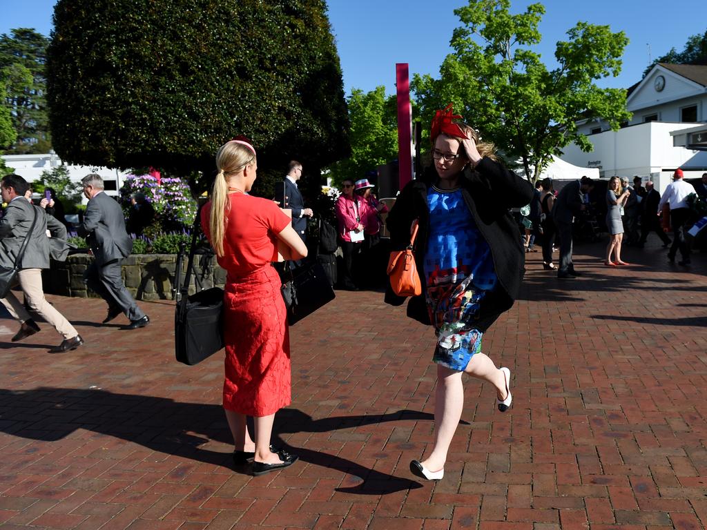 Punters run through the gates to get a good Melbourne Cup position at the finish line. Picture: AAP