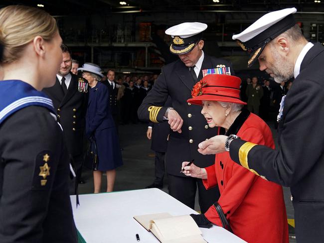 The Queen signs the visitors' book during her visit to the aircraft carrier HMS Queen Elizabeth in Portsmouth. Picture: AFP