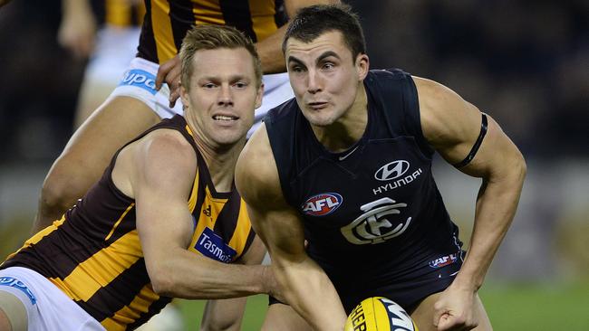 Under pressure from Hawk Sam Mitchell, Jaryd Cachia gets a handpass away for Carlton in 2013.