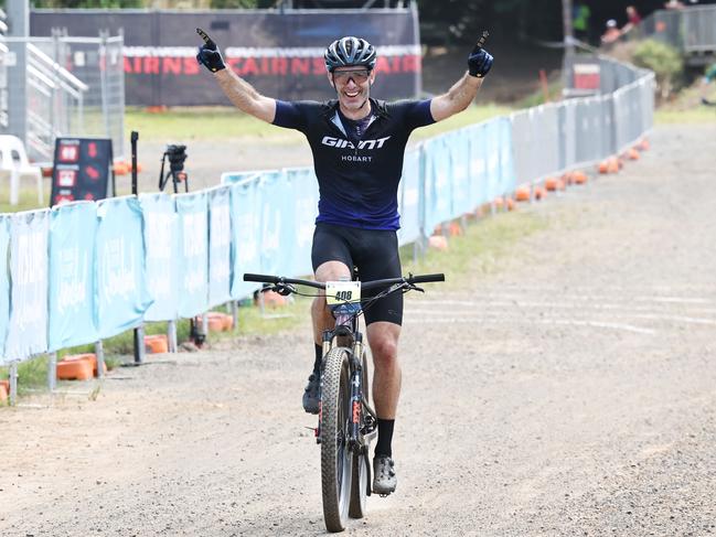 Mark Leis raises his arms in the air as he crosses the finish line to win the Male 50 to 54 years cross country class of the UCI Masters Mountain Bike World Championships, held at Smithfield Mountain Bike Park. Picture: Brendan Radke