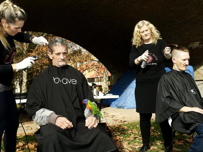 Ray Griffiths with his pet "Birdy" getting his hair cut by Lyndle Dryan and Sam Corliss’ hair is cut by Beth Shannon. Picture: John Appleyard