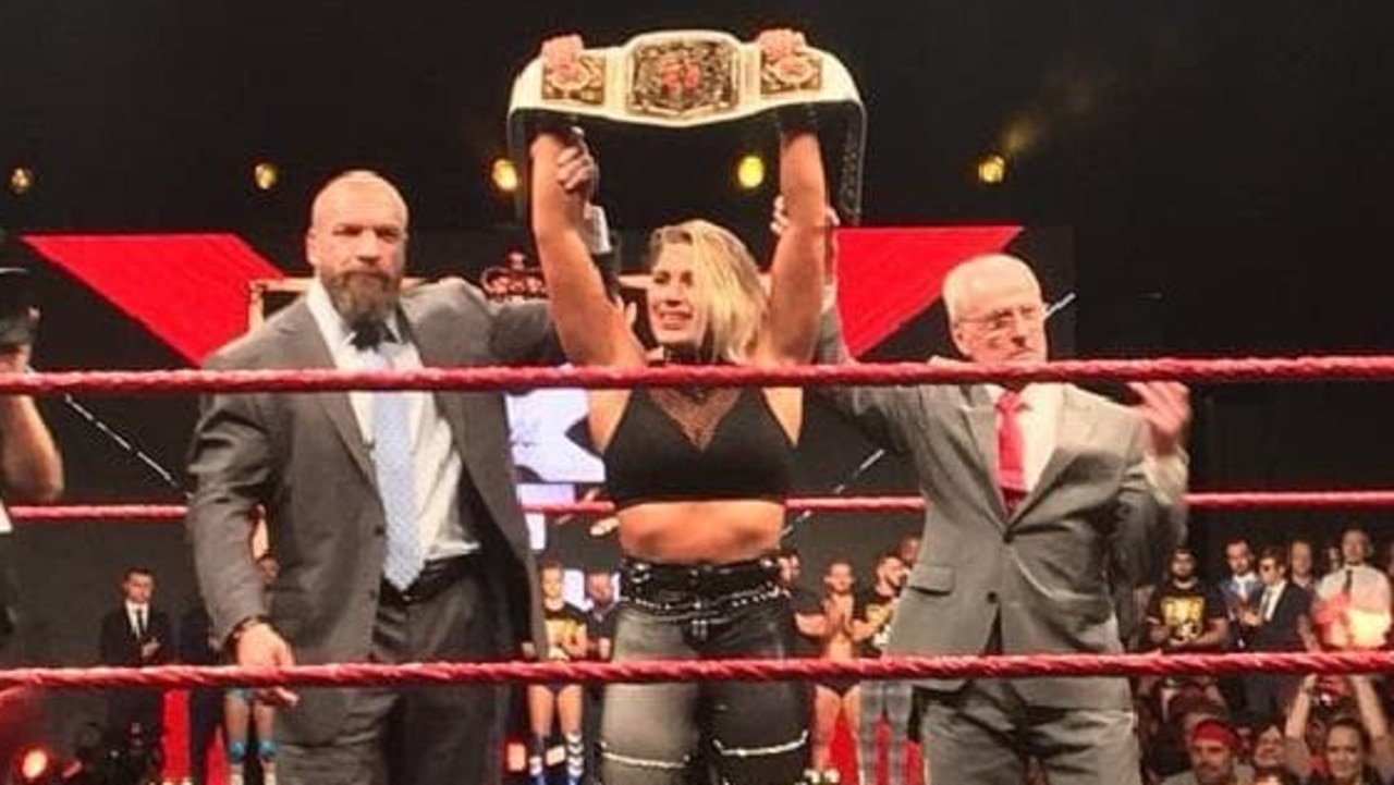 Australia's Rhea Ripley has become the first Aussie woman to win a championship in the WWE. Here she is with Triple H (left) and British wrestling legend Johnny Saint.