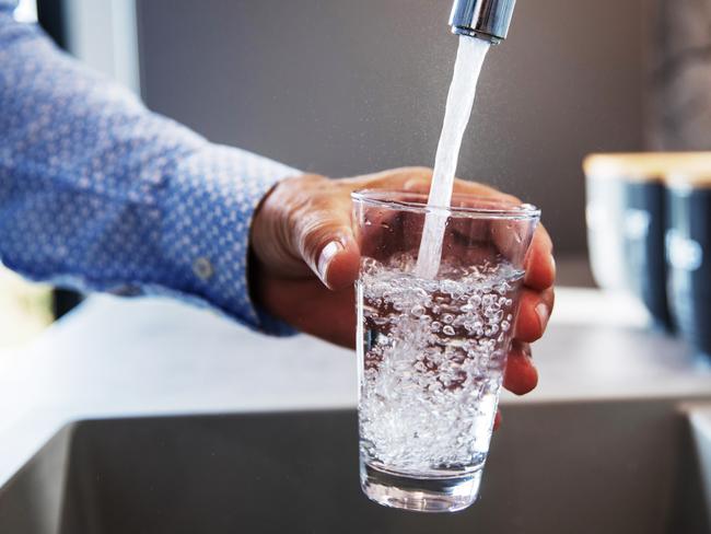 Mature male hand  pouring a glass of water from tap in the kitchen sink