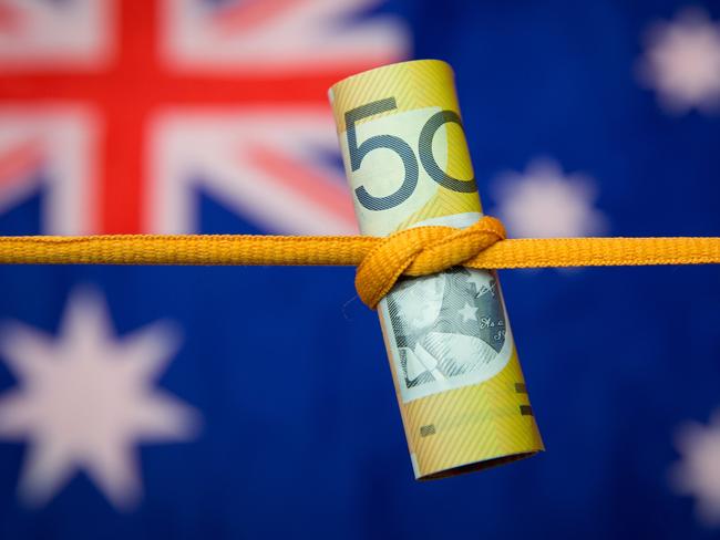 Studio shot close up of an Australian dollar note tied in a knot with the Australian flag as a background. Mortgage home loan money stress generic