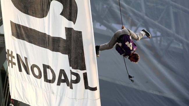 A protester wearing a Brett Favre jersey dangles upside down above Minnesota Vikings and Chicago Bears football game.