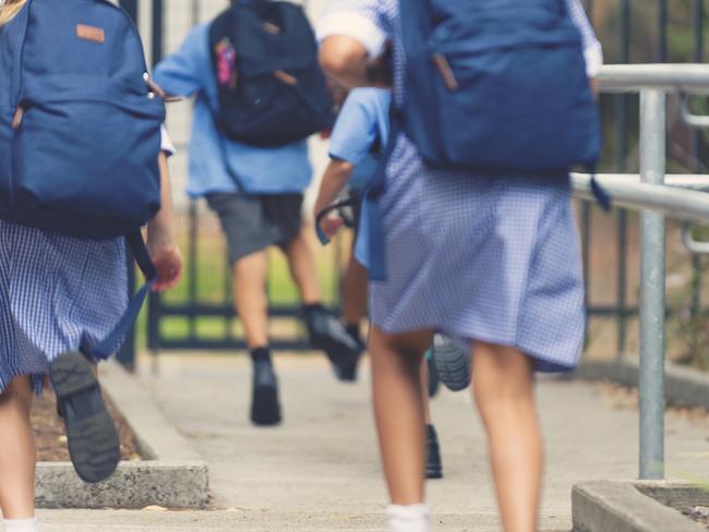 School children running away. They are wearing uniforms and carrying backpacks. They are having a race. Multi ethnic group with Asian, Caucasian and Aboriginal children. Rear view.istock image