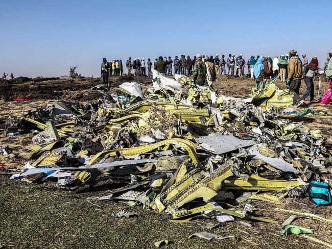 People stand near collected debris at the crash site of the Ethiopian Airlines plane near Bishoftu. Picture: AFP 