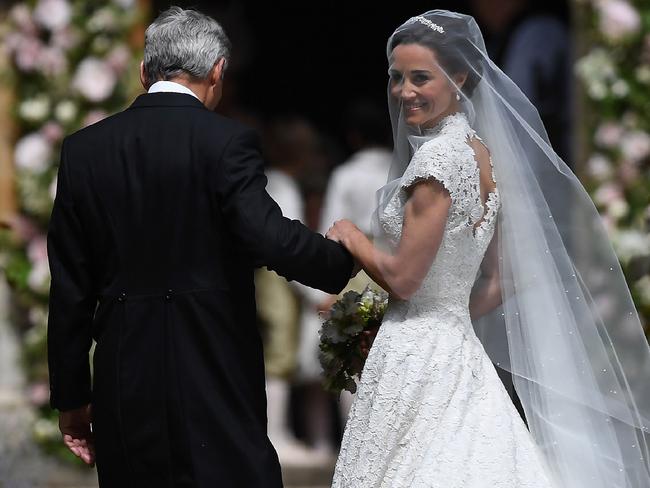 Pippa Middleton, (R) is escorted by her father Michael Middleton, as she arrives for her wedding to James Matthews at St Mark's Church in Englefield, west of London, on May 20, 2017. Pippa Middleton hit the headlines with a figure-hugging outfit at her sister Kate's wedding to Prince William but now the world-famous bridesmaid is becoming a bride herself. Once again, all eyes will be on her dress as the 33-year-old marries financier James Matthews on Saturday at a lavish society wedding where William and Kate's children will play starring roles. / AFP PHOTO / POOL / Justin TALLIS