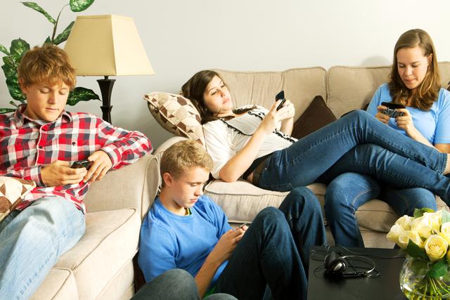 Teenagers texting on mobile phones in a home setting